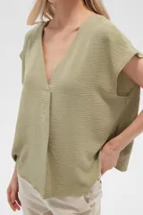 Blusa color verde oliva de poliéster, lisa, holgada y con cuello en V.