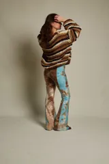 Pantalón de tiro medio con elástico en la cintura y corte acampanado. Diseño con estampado abstracto en tonos marrones, rojizos y amarillos, con textura tipo piel de reptil.