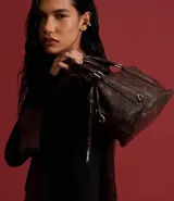 Cartera mini satchel con asa larga ajustable, confeccionada en material sintético PU, con cierre de cremallera y efecto desteñido.