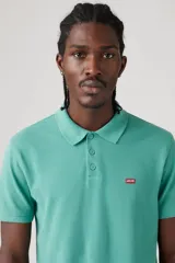 Chomba manga corta color celeste con cuello clásico y logo de la marca bordado en el pecho.