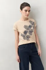 Remera blanca de manga corta con estampado floral en tonos dorados en el frente.