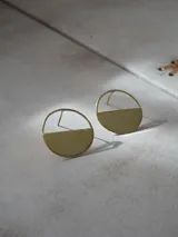 Par de aros dorados con forma circular, divididos horizontalmente: la mitad superior es un aro fino y la mitad inferior es un semicírculo sólido.