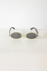 Lentes de sol ovalados con marco dorado y patillas negras.