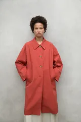 Chaqueta color beige, repelente al agua, con cuello clásico, cierre con botones, bolsillos laterales y corte holgado. Fabricada con poliéster reciclado y algodón orgánico.