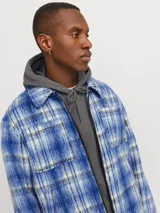 Campera con cierre frontal, cuello clásico, mangas largas con puños abotonados y bolsillos en el pecho y delanteros. Diseño a cuadros azules y blancos.