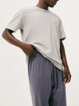 Pijama gris compuesto por una remera de manga corta con cuello redondo y un pantalón largo. La remera tiene un pequeño bordado en el pecho.