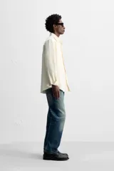 Camisa color crudo de algodón con acabado cepillado, corte relaxed fit, cuello solapa, manga larga con puño abotonado, bolsillo de parche en el pecho, efecto lavado y cierre frontal abotonado.