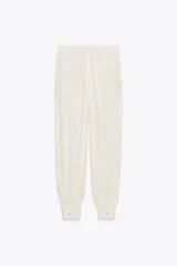Pantalón de tiro medio color crudo con rayas verticales, confeccionado en hilatura con lino. Tiene bolsillos laterales ocultos en costura y de vivo en espalda, detalle de pliegues y bajo acabado en puño.