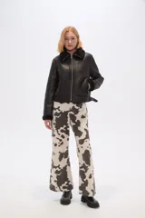 Campera corta negra de cuero sintético con cuello y puños de piel sintética negra, cierre frontal con cremallera y bolsillos laterales con cremallera.