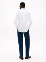 Camisa blanca de corte regular confeccionada en tejido dobby de puro algodón, con cuello inglés, puños redondeados con botón y logo de Tommy Hilfiger bordado en el pecho.