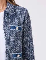 Chaqueta de tweed azul con cuello a la base, abertura central y bolsillos delanteros. Presenta puños con aplique de botones perlados y terminación desflecada. Incluye forro interno.