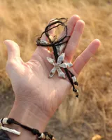 Collar artesanal con dije de flor plateada, realizado con hilo de seda natural teñido a mano.