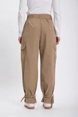 Pantalón cargo color beige con cinturón con hebilla metálica, bolsillos laterales con solapa y ajuste con hebilla en los tobillos.