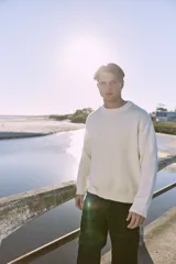 Sweater blanco de tejido plano, con cuello redondo, corte oversize y hombros caídos.