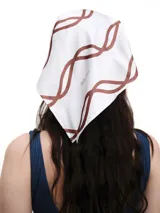 Pañuelo de seda con estampado que evoca ondas del mar, en tonos blanco y marrón.