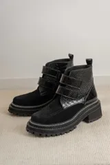 Botas cortas negras de cuero con detalle de textura tipo cocodrilo en la parte superior y ajuste con velcro.