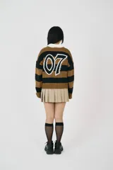 Sweater estilo rugby a rayas horizontales color marrón y negro, con cuello tipo polo blanco de botones, logo bordado en el frente y detalle intarsia 07 en la espalda.