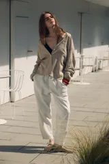 Pantalón color beige de tiro medio con cintura elástica ajustable con cordones, bolsillos delanteros y falsos bolsillos de vivo en la espalda. El bajo es ajustable con botón a presión.