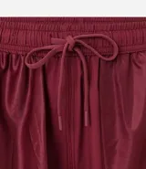 Bermuda deportiva color beige, de tejido plano de poliéster, con cintura elástica y cordón de ajuste. Posee bolsillos laterales con cierre y recortes laterales con perforaciones.