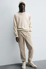 Pantalón jogger negro de corte slim fit, confeccionado en tejido de algodón con cintura elástica ajustable con cordón, bolsillos frontales y traseros de vivo, y bajo con puño elástico.