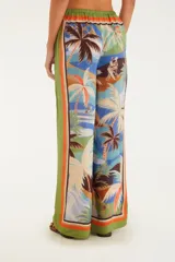 Pantalón largo de corte fluido con estampado de palmeras y motivos playeros, cintura alta con cordón ajustable y ribete naranja en ruedo y laterales.