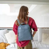 Mochila negra de símil cuero con costuras diagonales en el frente. Tiene un bolsillo frontal con broche magnético, asa de mano y correas regulables.
