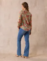 Blusa de gasa estampada a rayas verticales en tonos celeste, lila, naranja y marrón. Tiene cuello a la base con escote en V y botones. Delantera con bolsillo aplicado. Largo de manga regulable con presilla y botón. Terminación anudada opcional.