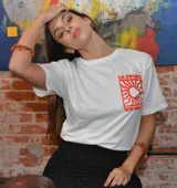 Remera blanca de algodón con estampa roja en la espalda que incluye el texto "LE SOLEIL" y un sol estilizado.