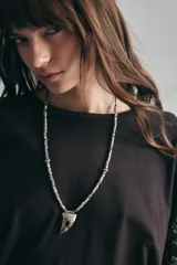 Collar regulable con cadena de piezas metálicas facetadas y un dije en forma de cuerno con piedra incrustada, de estilo bohemio.