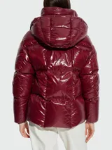 Campera corta acolchada de plumas, con acabado brillante. Presenta un diseño bicolor: exterior en color borgoña/vino y forro interior en rosa pálido. Tiene capucha y cierre frontal.