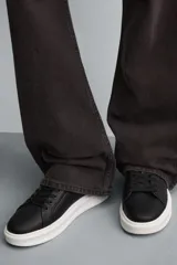 Zapatillas deportivas negras con detalle en blanco en el talón y suela blanca con volumen.