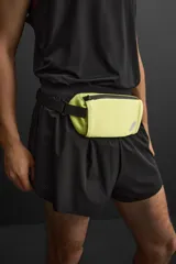 Riñonera deportiva color amarillo flúor, con cierre de cremallera termosellada, bolsillo interno con cremallera y doble mosquetón. Cuenta con banda elástica frontal y asa ajustable con hebilla de liberación rápida.