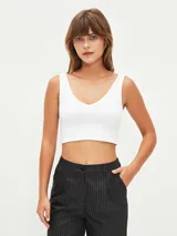Top blanco de corte cropped con escote en V, ideal para combinar con otras prendas.