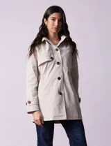 Gabardina impermeable color beige, marca Weatherproof, con abertura central con botones, bolsillos delanteros y capucha desmontable.