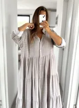 Vestido camisero largo color gris con rayas verticales blancas, cuello camisero, mangas 3/4 con puños blancos y cierre frontal con botones.