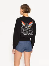 Buzo negro de algodón con cuello redondo y mangas largas. Presenta un pequeño corazón rojo estampado en el frente y un diseño de ángel en la espalda. Corte amplio y largo hasta la primera cadera.