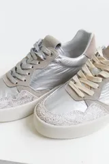 Championes de cuero color plateado con detalles en gamuza color beige y suela blanca. Incluye dos pares de cordones de diferentes colores.