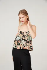 Musculosa con estampado floral multicolor sobre fondo negro, breteles anchos y escote cuadrado.