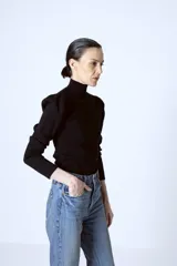 Polera roja de tejido de punto con cuello alto y mangas largas abullonadas en los hombros.