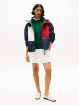 Campera náutica amplia reversible de nailon, con diseño color block en rojo, blanco y azul marino. Tiene capucha fija, cierre de cremallera oculto con botones a presión, puños y bajo elásticos, dos bolsillos ribeteados en la cintura, parche con logo de Tommy Hilfiger en el pecho y logo de Tommy Hilfiger en el cuello, las mangas y la espalda.
