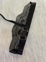 Conjunto de lencería de encaje negro, compuesto por un corpiño triangular con breteles regulables y collarín central con cuello regulable, y una tanga regulable de corte media less con entrepierna de algodón.