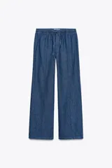 Pantalón de jean azul con cintura elástica ajustable con cordones, tiro medio y bolsillos de parche en la parte trasera.