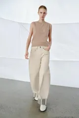 Jeans de tiro medio color beige, corte relaxed leg y largo al tobillo. Cuentan con cinco bolsillos y bajo con vuelta a contraste en gris. Cierre frontal con cremallera y botón.