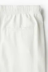 Pantalón blanco de lino con corte recto, cintura elástica y cordón ajustable.