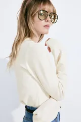 Cárdigan color crema de punto suave con lana en la trama. Modelo con cuello redondo ribeteado acanalado, cierre frontal con botones, remate acanalado en puños y bajo.