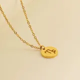 Collar dorado con dije redondo con el signo de Aries grabado.