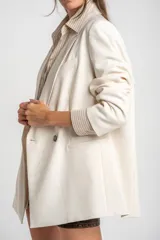 Blazer color crema, de corte oversize, con solapas de muesca, cierre con doble botón y bolsillos laterales con solapa.