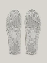 Zapatillas urbanas Tommy Jeans de corte bajo, con exterior de piel en tonos blanco, gris y beige. Presentan suela gruesa de goma, cordones y logo de la marca en el lateral y el talón.