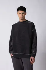 Buzo negro de frisa 100% algodón, con calce oversize y lavado gastado. Tiene costuras a contratono y recortes.