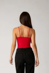 Top negro de algodón acanalado, ajustado al cuerpo, con cuello halter asimétrico y detalle de aro de madera en el centro del escote.